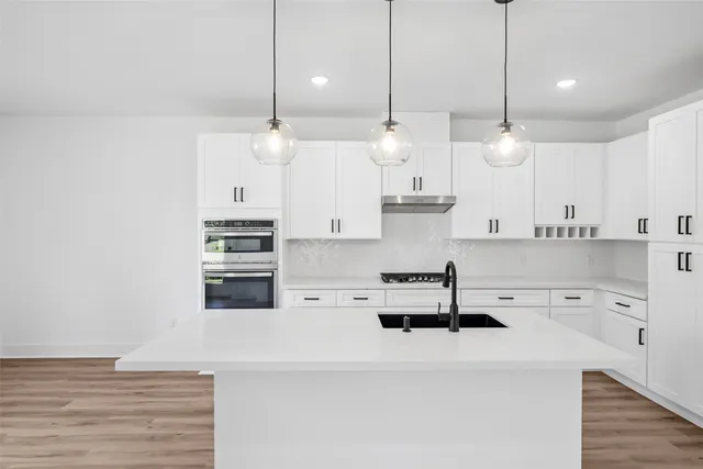 a kitchen with kitchen island a stove a sink and a wooden floor