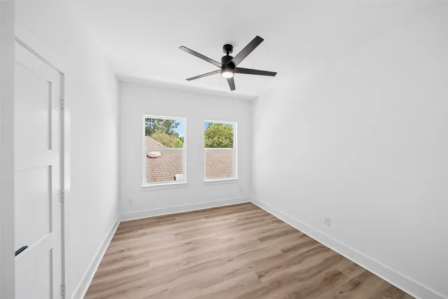 an empty room with a window and a ceiling fan