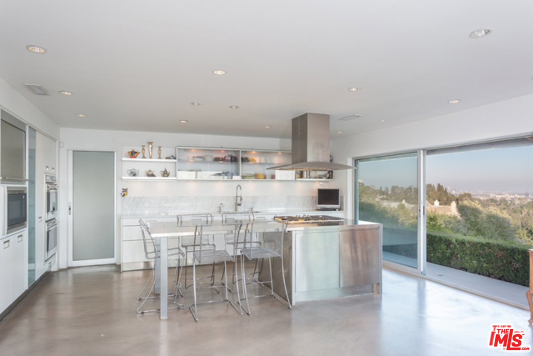 1230 Shadow Hill Way Beverly Hills, CA 90210 - Photo 9 of 22 a kitchen with kitchen island a table and chairs
