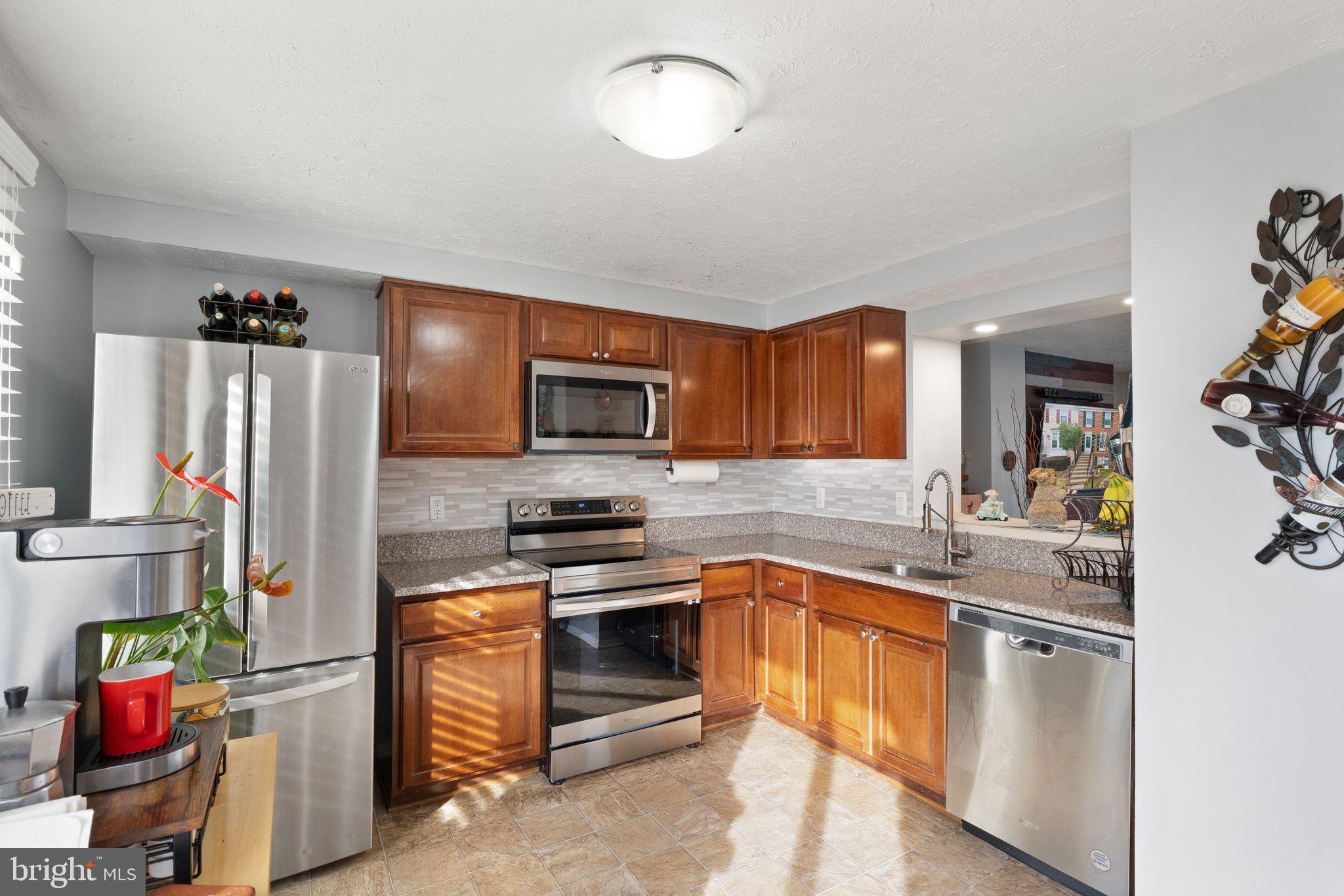 7457 Wounded Knee Road Lorton, VA 22079 - Photo 12 of 49 a kitchen with stainless steel appliances granite countertop a sink stove and refrigerator