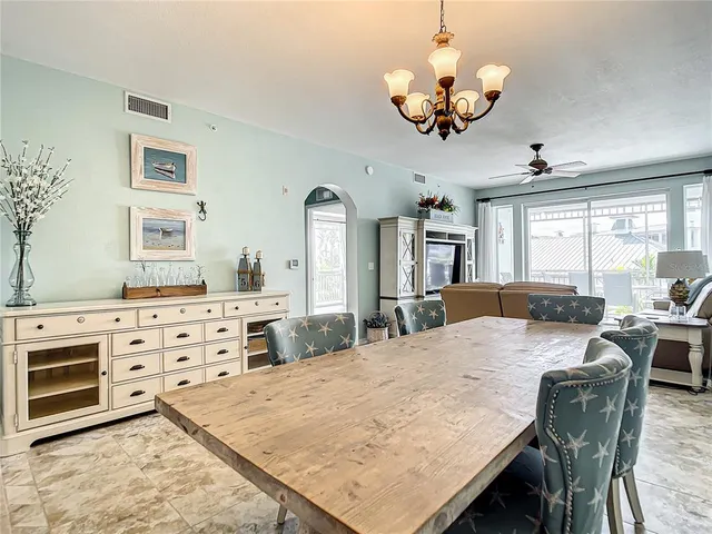 a kitchen with stainless steel appliances granite countertop a sink a stove a refrigerator and chairs with wooden floor