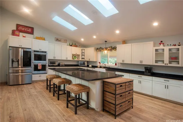 a kitchen with stainless steel appliances granite countertop a table chairs sink and cabinets