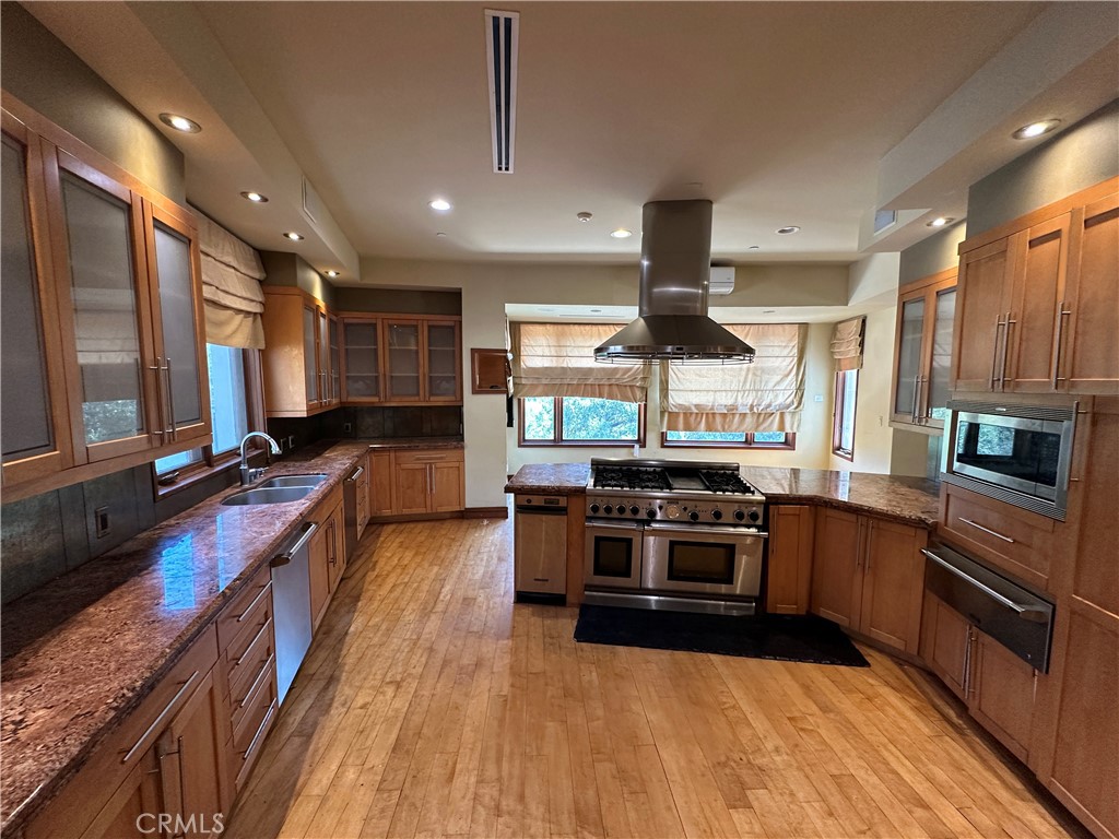 5077 Schumacher Road Calabasas, CA 91302 - Photo 11 of 58 a kitchen with stainless steel appliances granite countertop wooden cabinets a stove top oven a sink and dishwasher