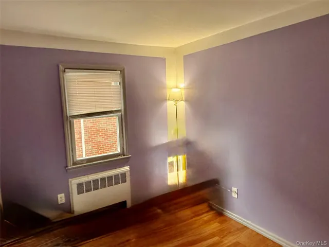 a view of an empty room with window and wooden floor