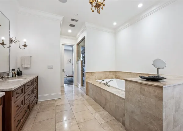 a spacious bathroom with a granite countertop double vanity sink a mirror a lamp a bathtub and vanity