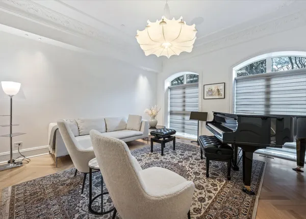 a dining room with wooden floor a chandelier a glass table and chairs