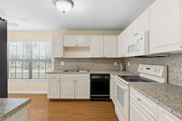 a kitchen with stainless steel appliances granite countertop a stove a sink and white cabinets