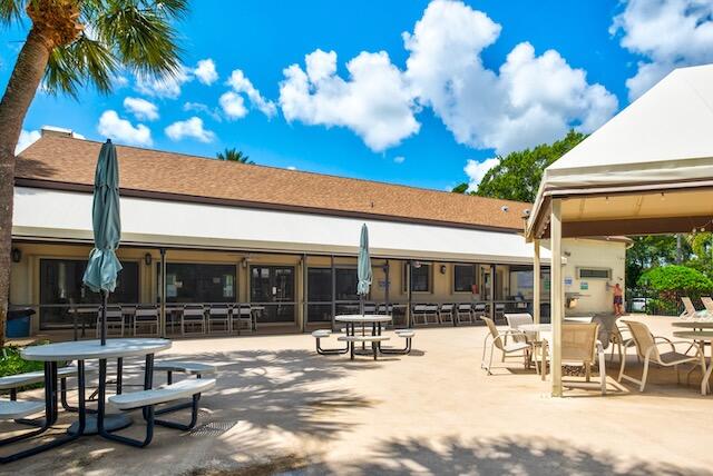 3233 Perimeter Drive, Unit 2511 Greenacres, FL 33467 - Photo 31 of 39 a view of a patio with dining table and chairs with a large tree