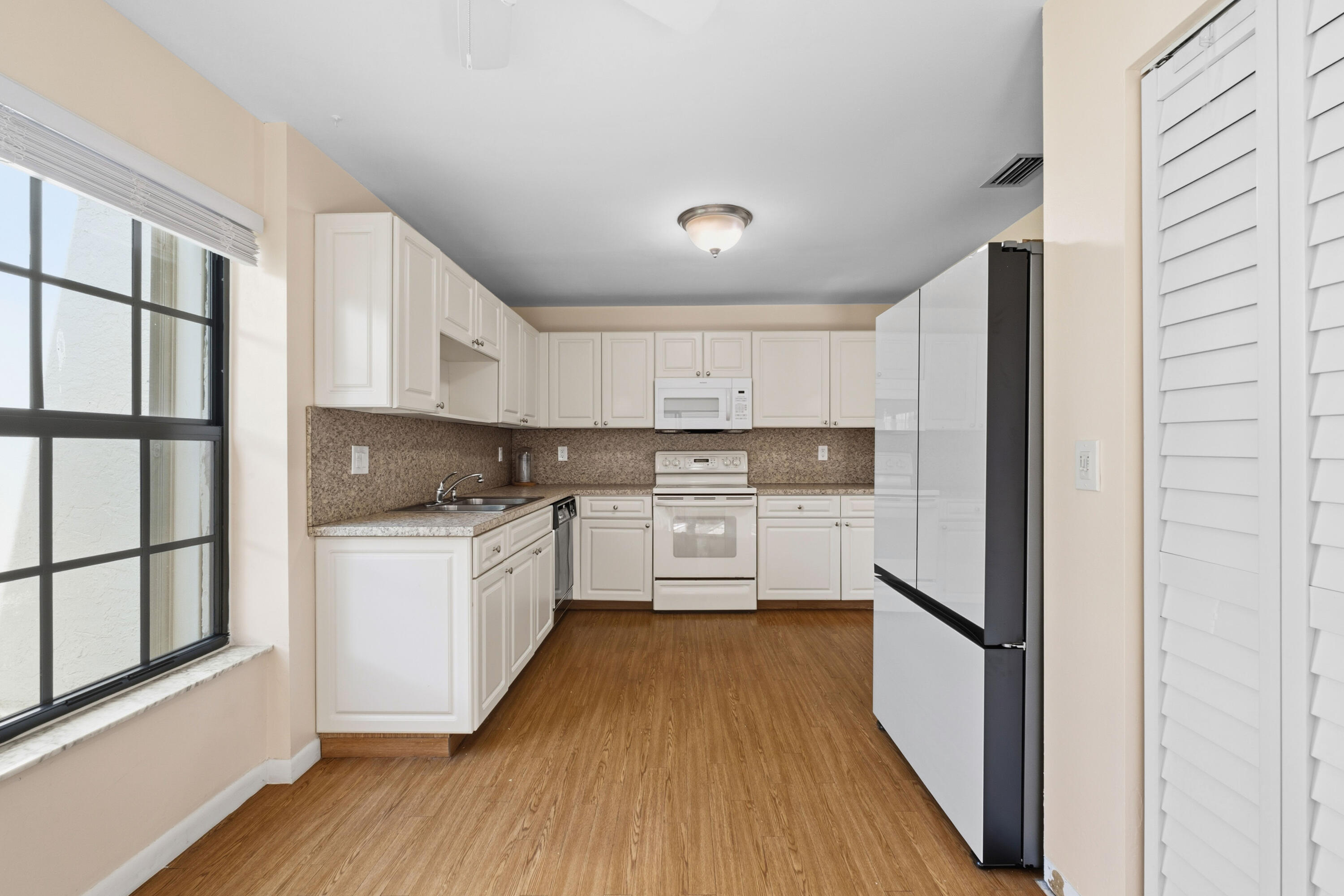 3233 Perimeter Drive, Unit 2511 Greenacres, FL 33467 - Photo 6 of 39 a kitchen with white cabinets and white appliances