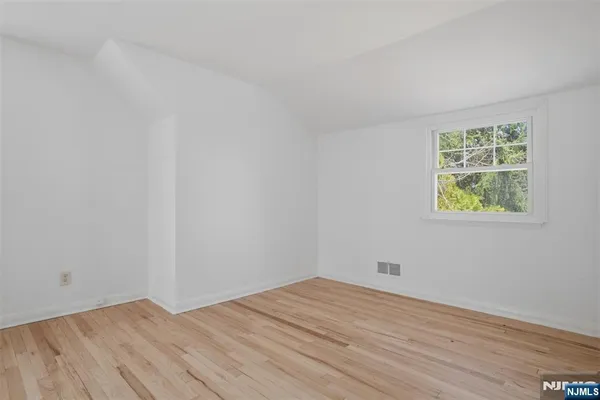 an empty room with a wooden floor and windows
