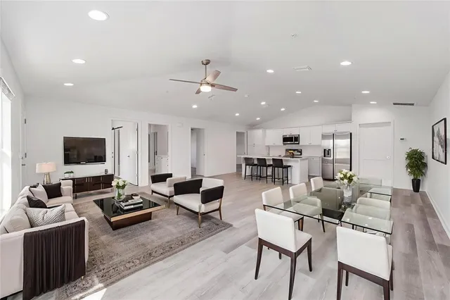 a living room with furniture kitchen view and a flat screen tv