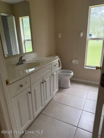 a bathroom with a toilet a sink a mirror and a window