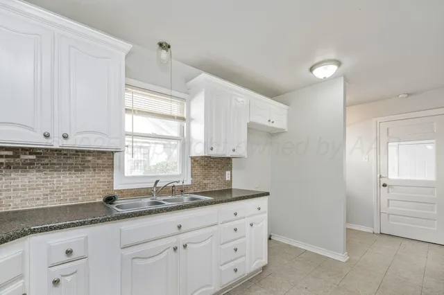 a kitchen with granite countertop white cabinets white appliances and a sink