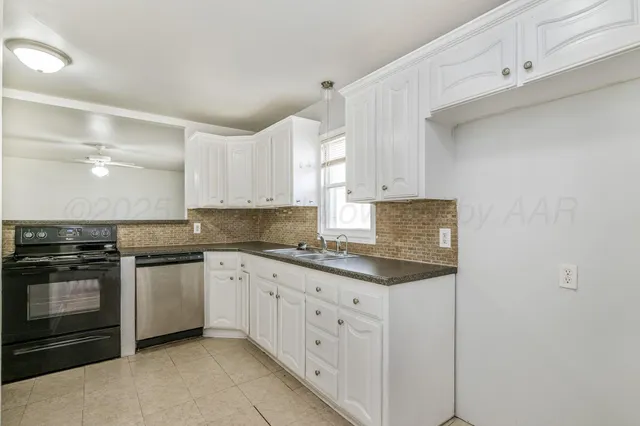 a kitchen with stainless steel appliances granite countertop a stove and white cabinets