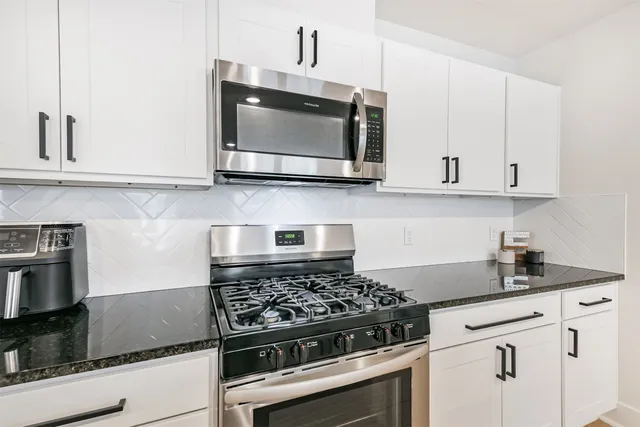 a kitchen with white cabinets and appliances