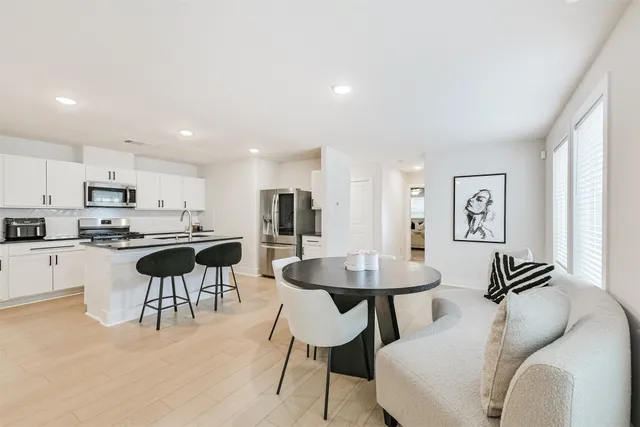 a kitchen with a dining table chairs stainless steel appliances and cabinets