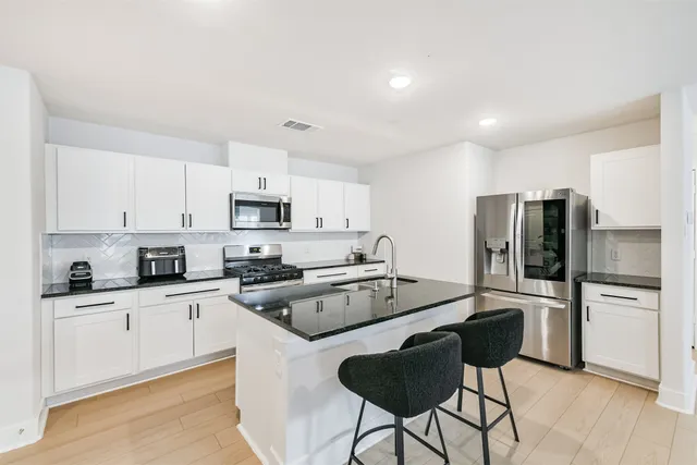 a kitchen with granite countertop a refrigerator stove microwave and sink