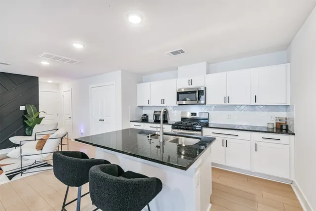 a kitchen with stainless steel appliances granite countertop a sink a stove a microwave a refrigerator and cabinets