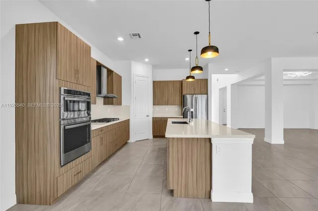 a large kitchen with stainless steel appliances kitchen island granite countertop a refrigerator oven a sink dishwasher and white cabinets with wooden floor