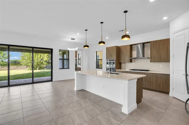 a large kitchen with kitchen island granite countertop a sink a counter and cabinets