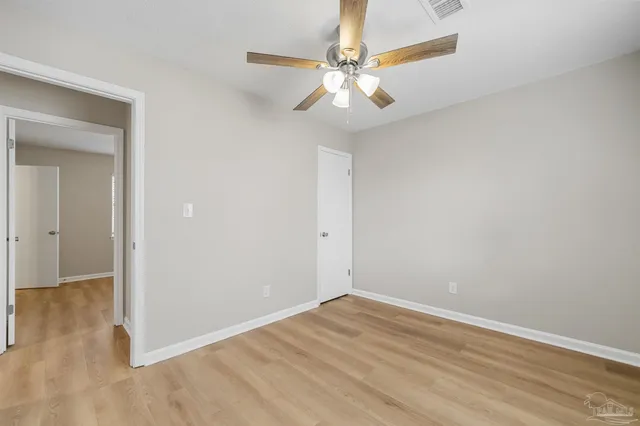 an empty room with wooden floor fan and window