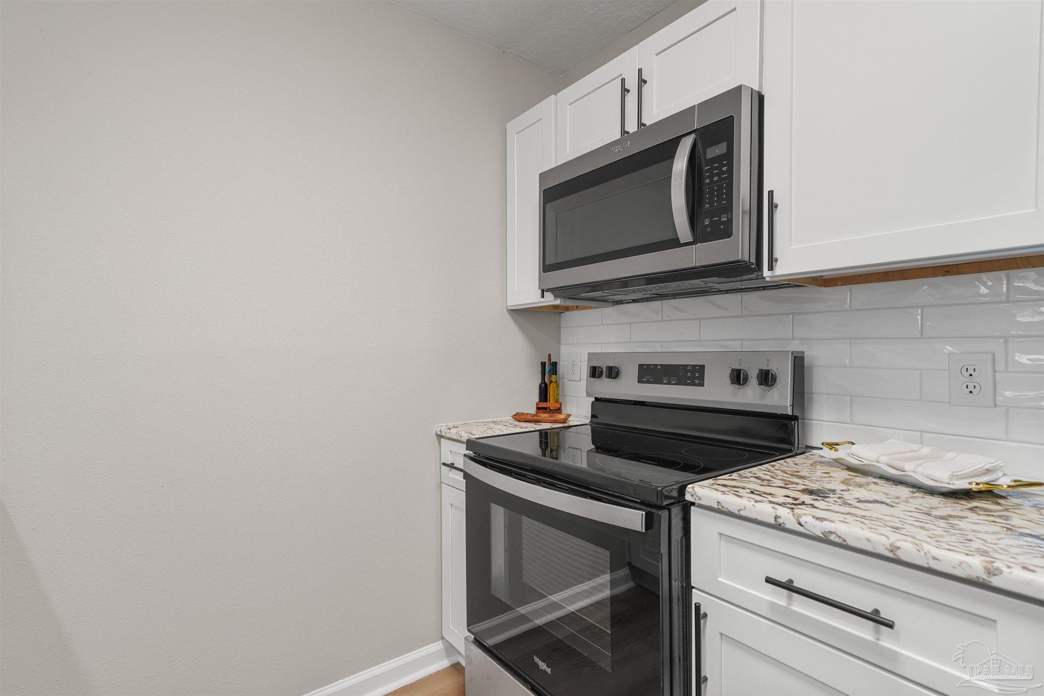 284 Dolan Drive Cantonment, FL 32533 - Photo 5 of 32 a kitchen with granite countertop white cabinets and stainless steel appliances
