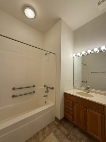 a bathroom with a tub sink double vanity and shower