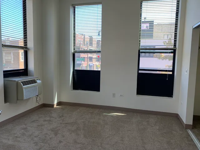 a view of an empty room with a kitchen and a window