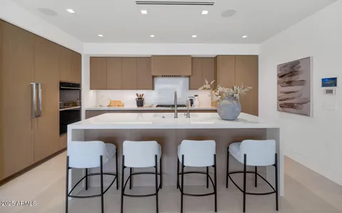 a kitchen with stainless steel appliances granite countertop a table chairs sink and cabinets