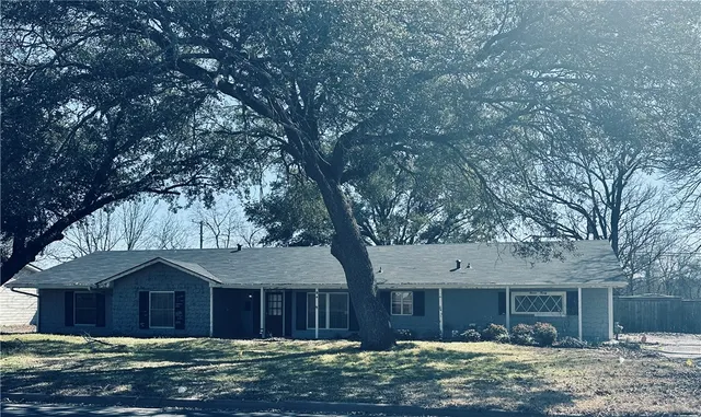 a front view of a house with a garden and trees