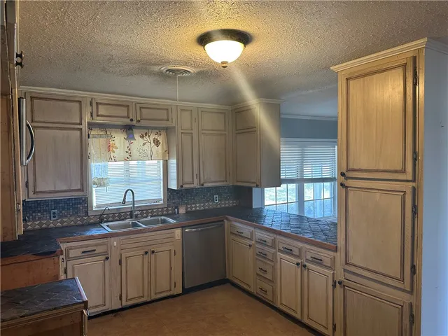 a kitchen with granite countertop cabinets stainless steel appliances a sink and a window