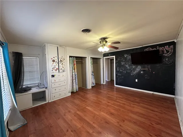 a view of an empty room with wooden floor and a kitchen