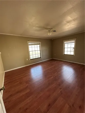 a view of an empty room with wooden floor and windows