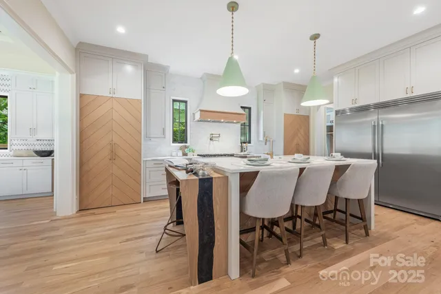 a kitchen with stainless steel appliances granite countertop a stove a sink dishwasher a refrigerator and white cabinets with wooden floor