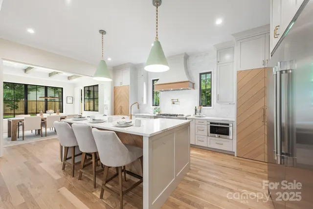 a large kitchen with kitchen island a stove a sink dishwasher a dining table and chairs with wooden floor