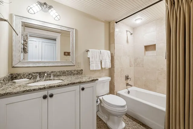 a bathroom with a granite countertop toilet sink and mirror