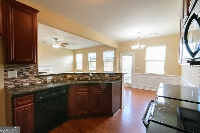 a large kitchen with stainless steel appliances wooden floor and a large window