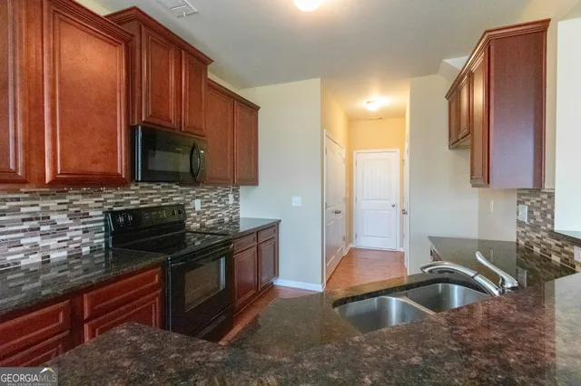 a kitchen with stainless steel appliances granite countertop a sink stove and microwave