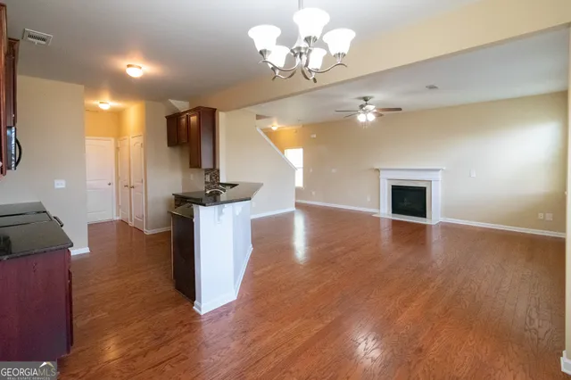 a view of a livingroom with a fireplace a chandelier and wooden floor