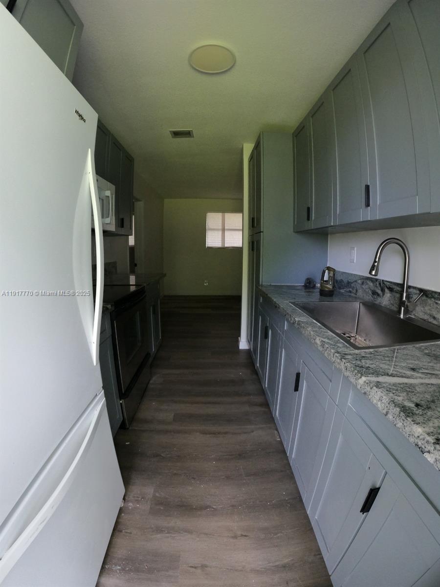 26633 Southwest 138th Court Homestead, FL 33032 - Photo 57 of 58 a kitchen with granite countertop a refrigerator and a sink