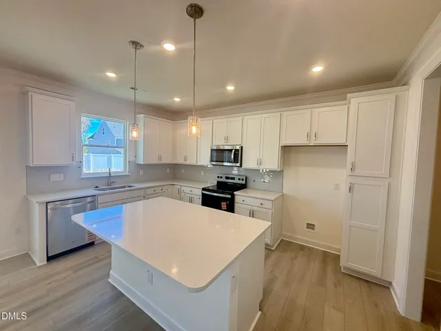 a kitchen with a refrigerator a sink dishwasher a stove and white cabinets with wooden floor