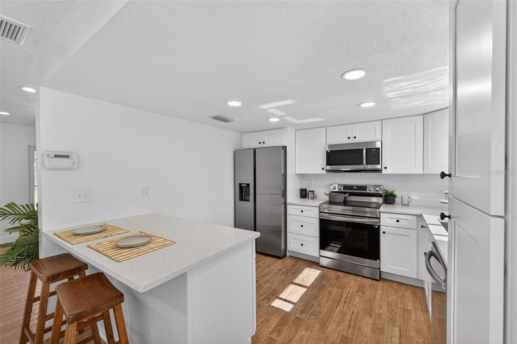 3733 Coppertree Circle Brandon, FL 33511 - Photo 6 of 45 a kitchen with stainless steel appliances a stove top oven a sink a refrigerator white cabinets and wooden floor