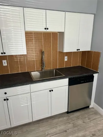 a kitchen with granite countertop white cabinets and sink