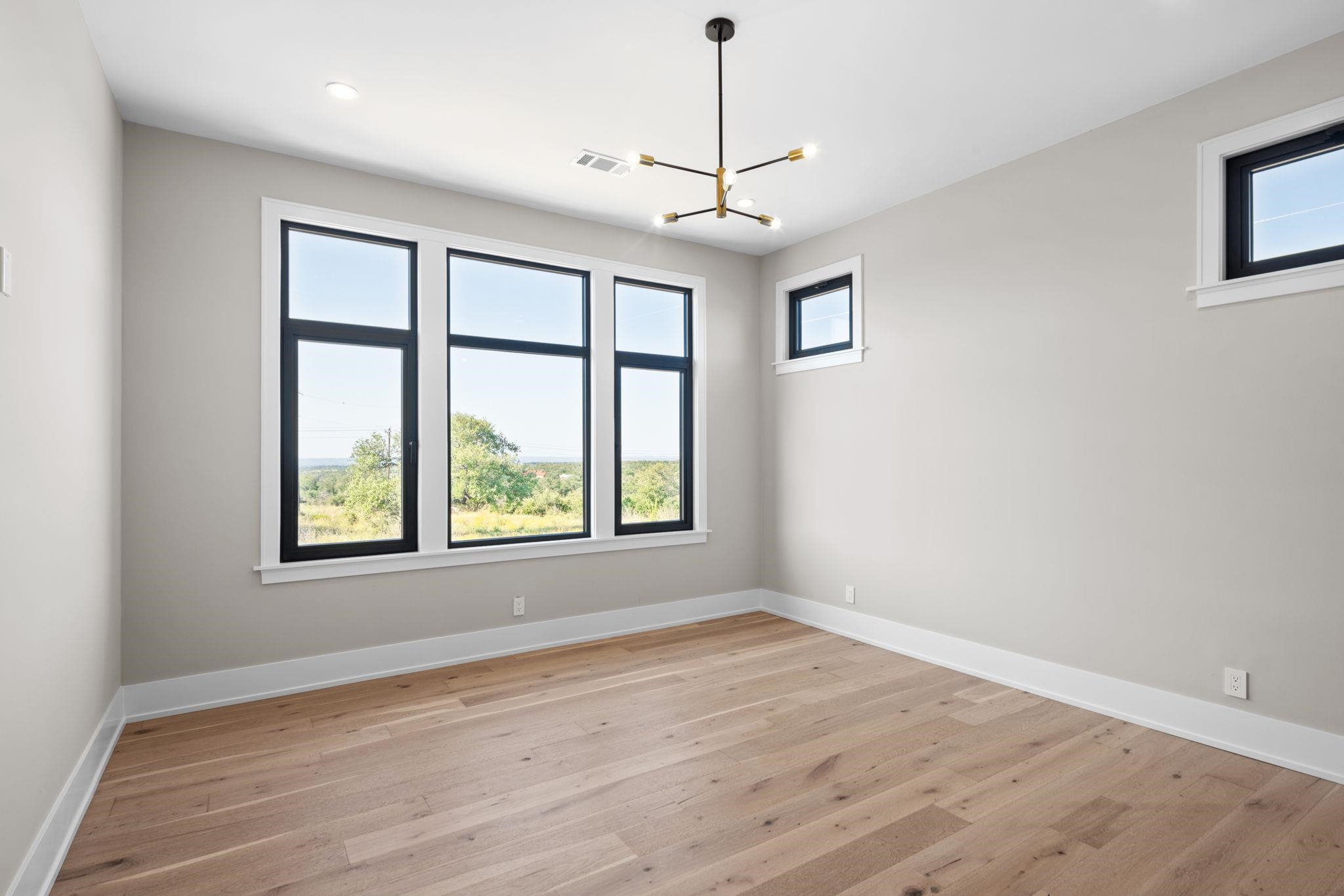 583 Comanche Ridge Round Mountain, TX 78663 - Photo 17 of 30 a view of an empty room with wooden floor and a window