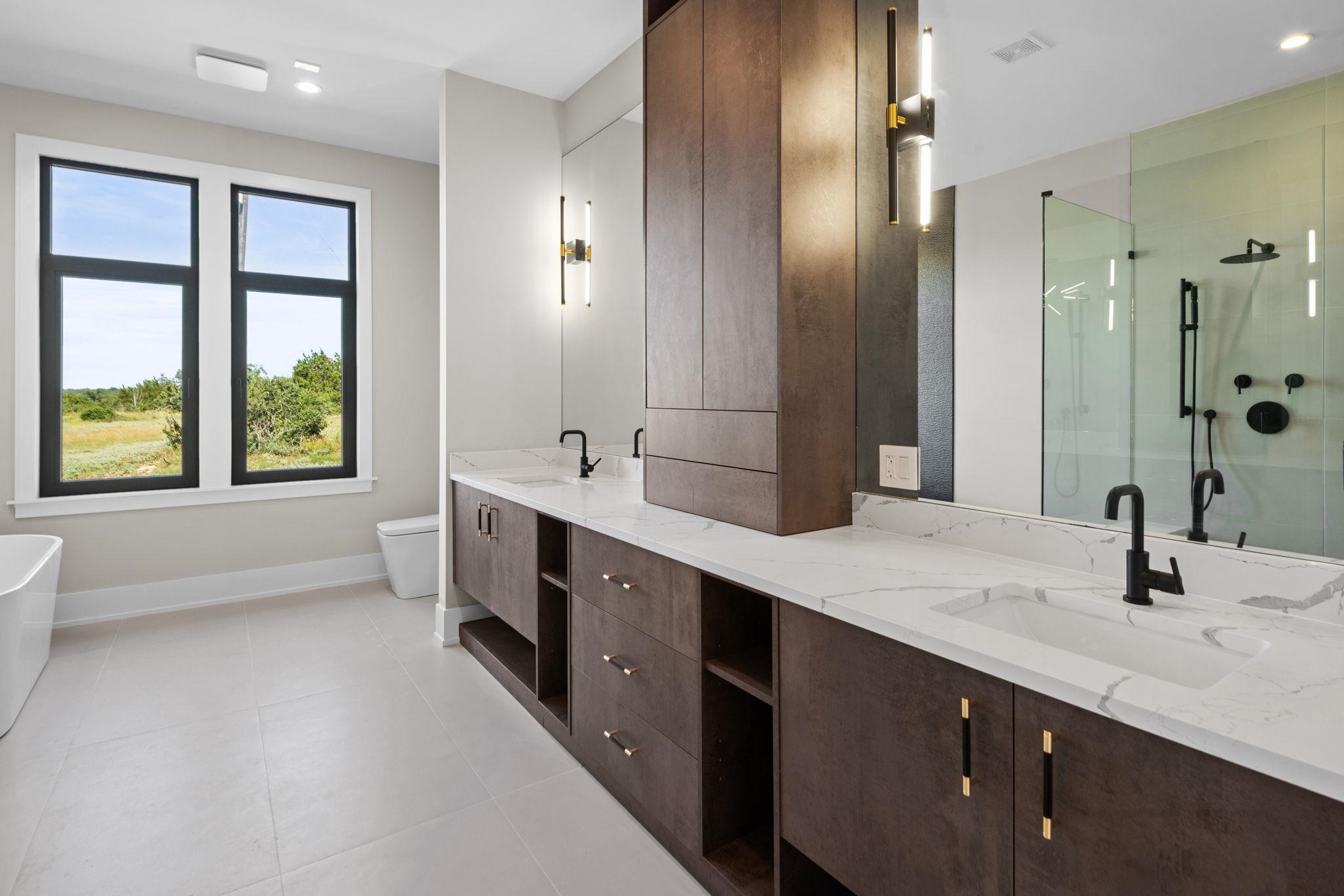 583 Comanche Ridge Round Mountain, TX 78663 - Photo 22 of 30 a bathroom with a double vanity sink a large mirror and a bathtub