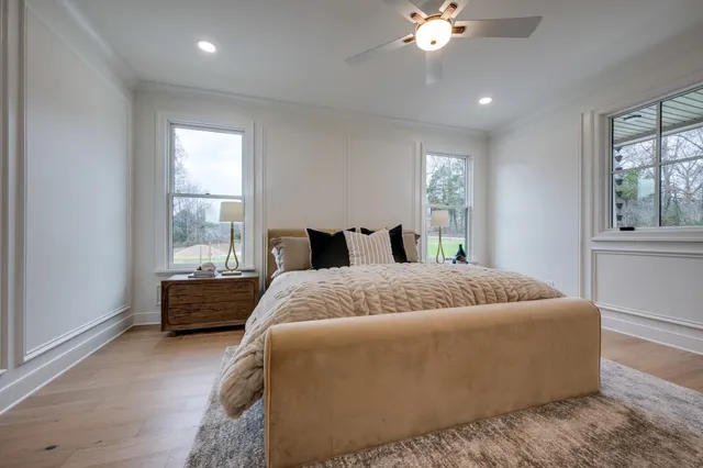 a bedroom with a bed a chandelier and mirror