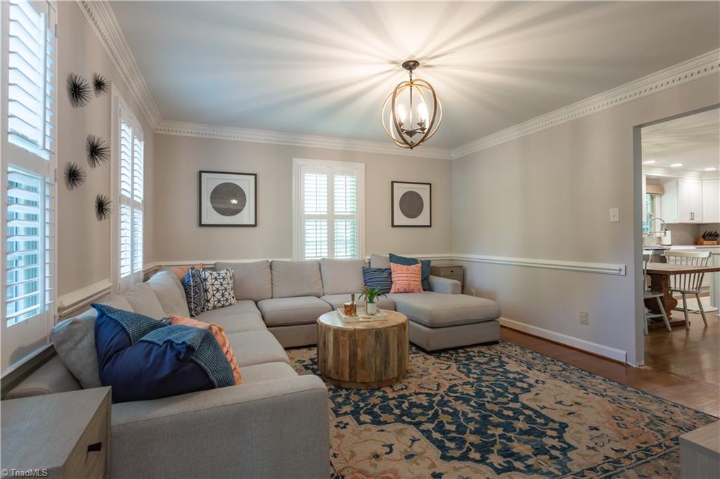 4200 Hobbs Road Greensboro, NC 27410 - Photo 6 of 36 Formal living room with updated fixture and vinyl windows with plantation blinds between dentil and chair rail moldings over gorgeous hardwood floors!