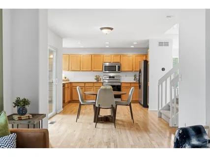 a open kitchen with stainless steel appliances kitchen island granite countertop a refrigerator a stove a microwave with a dining table and chairs with wooden floor