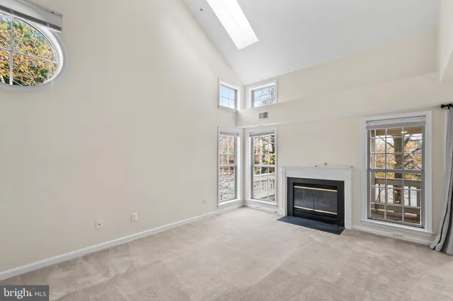 an empty room with windows fireplace and fans