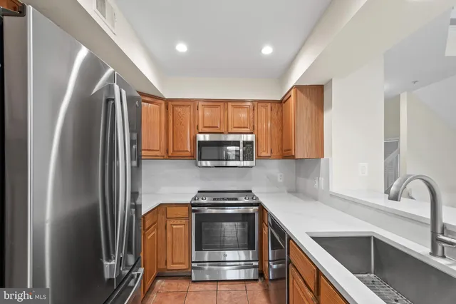 a kitchen with granite countertop a refrigerator and a stove top oven